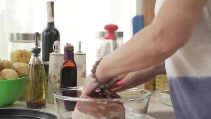 Hands seasoning meat with spices during cooking process